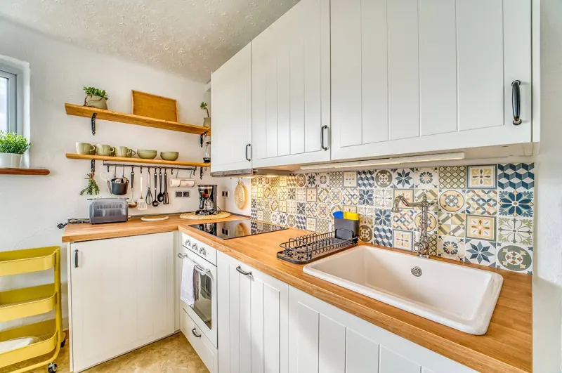 Fully equipped kitchen with colourful tiles and a wooden worktop